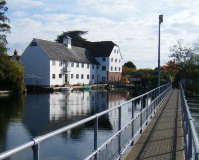 Photo over the River Thames to a large white painted building and a lock. Taken from a footbridge over Hambleden weir.